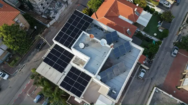 צילום רחפן של מבנה מסחרי עם מערכת סולארית על הגג לצד רחוב עירוני