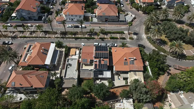צילום רחפן של שכונת מגורים עם כמה בתים שהתקינו מערכת סולארית