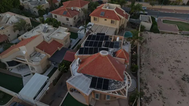 צילום רחפן של וילה עם גג רעפים בצורת מגדל, מערכת סולארית ובריכה בחצר